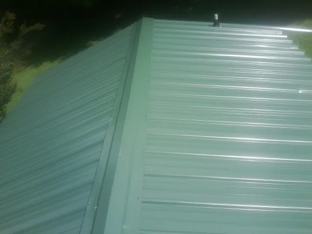 New green metal panels meeting at the ridge of a roof — Flat Roof Repair work by our crew in Laurier