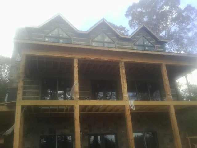 Dormers and porch framing on a large log home under construction — Roof Coating work by our crew in Laurier