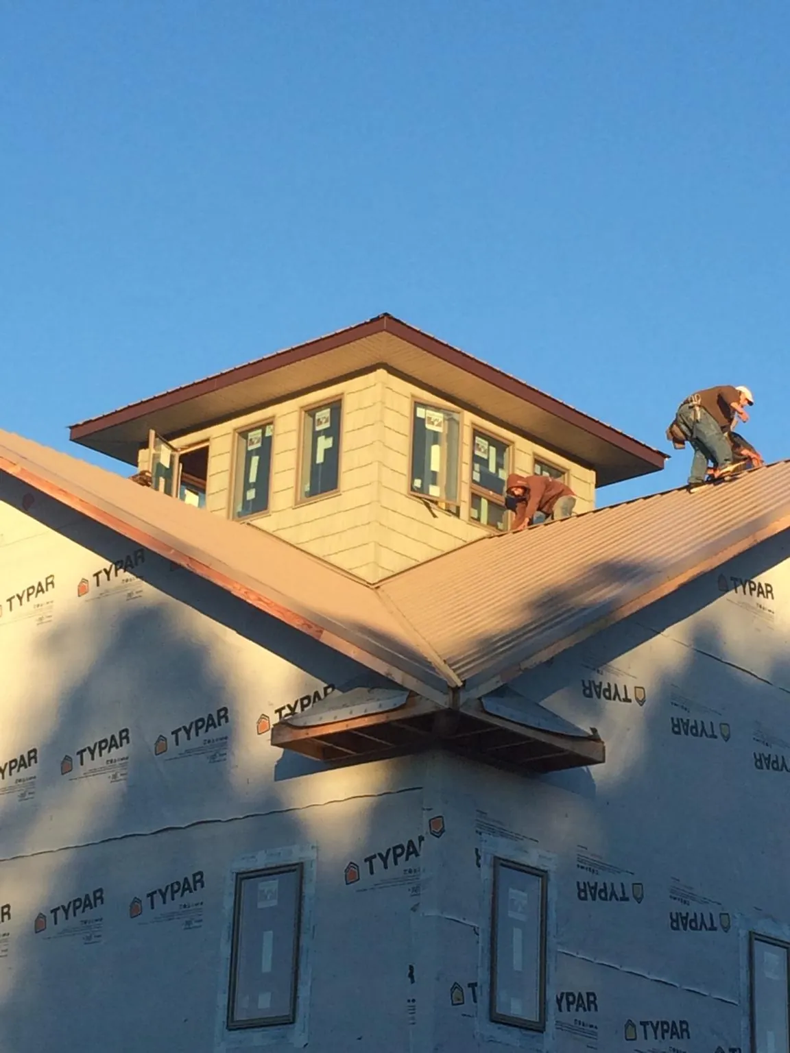 Roofers working around a rooftop cupola on a new metal roof at sunset — Roof Waterproofing in Laurier by Roofing Brothers